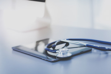 Medical equipment: blue stethoscope and tablet on white background