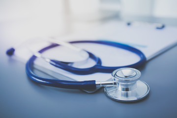 Stethoscope with black medical clipboard on wooden desk