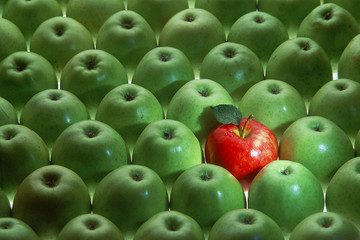 viele grüne und ein roter apfel als symbol