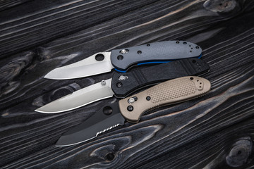 Folding knives on a wooden background