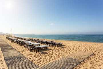Fototapeta na wymiar Rows of sunbeds for sunbathing on the beach in the Algarve.