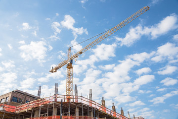 Working crane and safety net on modern office and residential building under construction against...