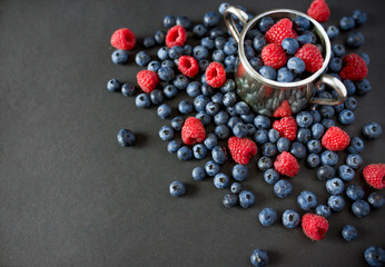 Background of raspberries and blueberries. Raspberry and blueberry on black background with copy space. Summer and healthy food concept, Top view or flat lay.