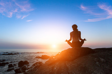 Yoga silhouette. Meditation woman on the ocean during amazing sunset.