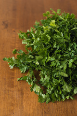 Bunch of fresh garden parsley stems with little imperfections on wooden background