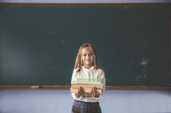 Portrait of little girl holding books in classroom