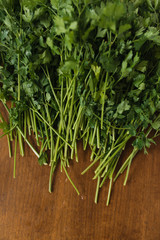 Bunch of fresh wet garden parsley stems with little imperfections on wooden background