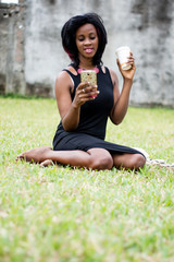 smiling young woman sitting in a park and using a mobile phone...