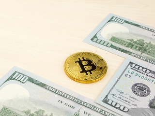 Golden bitcoin coin on us dollars close up.
