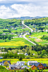 Les Eboulements, Charlevoix, Quebec, Canada cityscape or skyline with main highway steep curvy road going vertically up, patch farm green dandelion field, scattered village houses