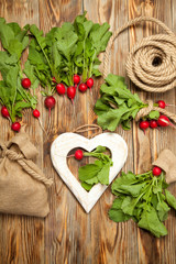 Red radishes in a wooden bowl on old table.