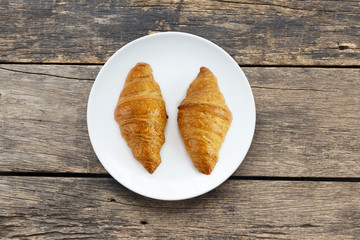 Croissant In white plate placed on a wooden table top view