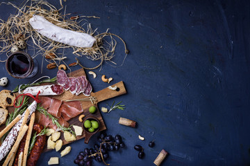 Charcuterie snacks on wood background. Salami and cheese served with red wine.