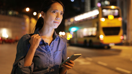 Woman use of taxi app on cellphone and waiting at outdoor