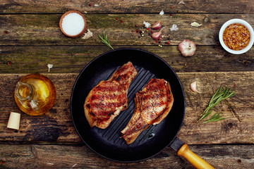 Grilled pork chops in a grill pan  on an old wooden table. Top view, flat lay.