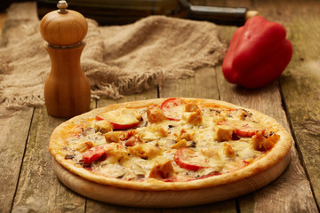 Chicken pizza pepper mill, sweet pepper and wine bottle on a rustic wooden table. Selective focus.
