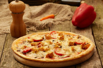 Chicken pizza pepper mill, chili, sweet pepper and wine bottle on a rustic wooden table. Selective focus.