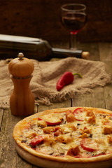 Chicken pizza pepper mill, chili, sweet pepper and wine bottle on a rustic wooden table. Selective focus.