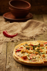 Chicken pizza pepper mill, chili  and wine bottle on a rustic wooden table. Selective focus.