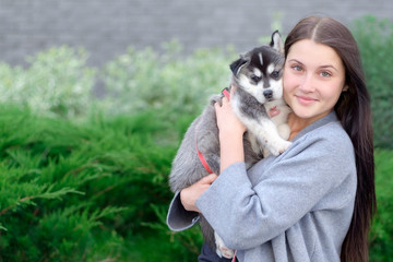 Smiling woman holding cute husky puppy