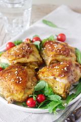 Baked chicken thighs with garnish of arugula and tomatoes. Rustic style, selective focus.