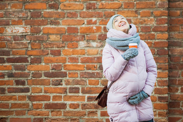 Pregnant woman with coffe laugh on vintage red brick wall