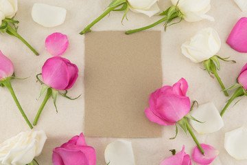 Blank brown card decorated with white and pink roses on white muslin fabric with copy space