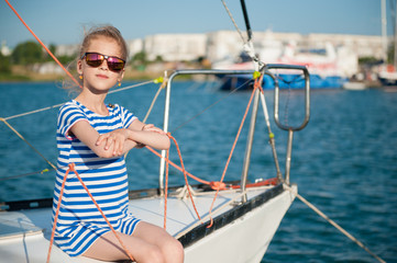 happy rich little girl sitting aboard white luxury yacht during summer sea cruise