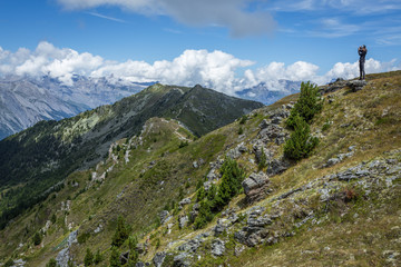 une jeune femme sur le haut d'une colline devant un paysage alpin