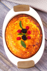 Cheesecake, garnished with raspberries, blackberries and mint. Homemade cheese cake. Closeup on table, vertical view from above, top shot