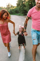 Young family portrait, mother, father and daughter having fun together and hug each other