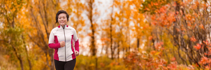 Autumn running middle age Asian woman jogging in park banner panorama. Active lifestyle mature lady...