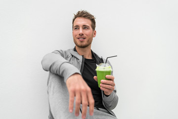 Healthy man drinking green smoothie spinach juice at home relaxing. Young adult eating detox diet,...