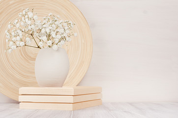 Soft home decor of beige bamboo dish and white small flowers in ceramic vase  on white wood background. Interior.