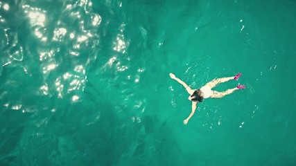 Obraz premium Aerial top down view of a beautiful young woman swimming in the sea
