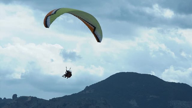 Paraglider fly above the mountains and the sea bay