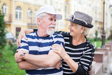 Loving elderly couple posing on camera. Pensioners hug each other. Happy old people.