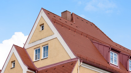 Mehrfamilienhaus mit Spitzdach vor blauem Himmel