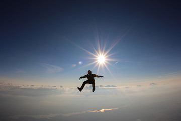 Alone skydiver is in the sky near the sun.