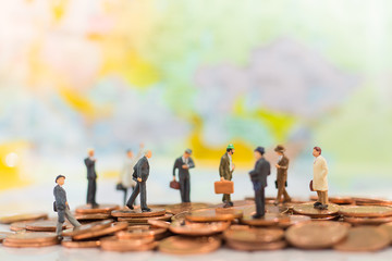 Miniature people: small figures businessmen stand on top of coins. Business Growth concept.
