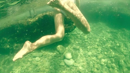 Beautiful young woman in white swimsuit bathing in the sea, underwater shot