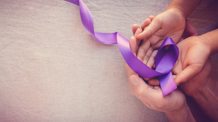 Hands holding Purple ribbons, toning copy space background, Alzheimer disease, Pancreatic cancer, Epilepsy awareness, domestic violence awareness - obrazy, fototapety, plakaty