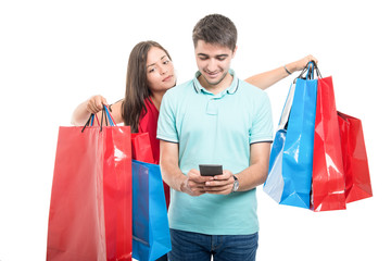 Girlfriend carrying shopping bags and boyfriend texting