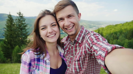 Fototapeta premium Happy couple doing selfie on a background of beautiful mountains. Magnificent vacation and vacation. 4K slow motion video