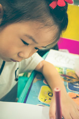 Happy asian boy painting blue color on artwork with paintbrush.