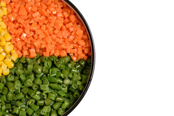 Three color vegetable platter: diced orange carrot, green bean and yellow corn kernel, on white background with negative space.