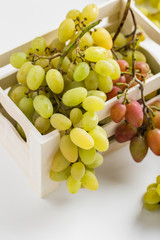 Closeup of green grapes in a wooden box on white background