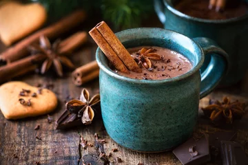 Door stickers Chocolate Hot chocolate with a cinnamon stick, anise star and grated chocolate topping in festive Christmas setting on dark rustic wooden background