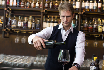 Handsome sommelier man Pour wine to the glass in restaurant, Man present Wine to Customer, Man with Sommelier Concept.