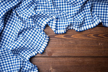 Blue checkered tablecloth on an old wooden table. Close up